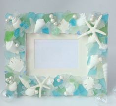 a photo frame made out of sea glass and seashells