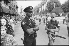 two police officers standing next to each other in front of a large group of people