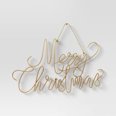 a merry christmas sign hanging from the side of a white wall with gold lettering on it