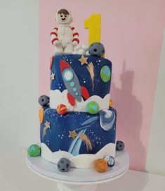 a birthday cake with an astronaut on top and space themed decorations around the bottom tier