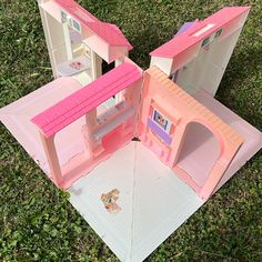 two pink dolls houses sitting in the grass