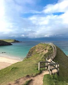 stairs lead down to the beach on a cloudy day with blue sky and water in the background