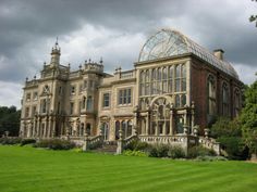 a large building with many windows on the side of it and green grass in front