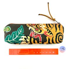 "Atenti Tool Pouch in a fun fabric print called LeTigre with the a Tiger face on the front and tail on the backside. Zipper pull is a Teal Ultra-Suede fabric with a 10\" zipper opening, fully lined in water repellent taffeta. A little vegan notions bag, tool bag, or pencil bag in a woven fabric. This pouch can  be used for a pencil bag, crafting tools, crochet tools, sewing notions anything you need to organize and move. A very beautiful Atenti Knitting Tool Case. Super fun knitter's gift, crafter's gift, student gift or Mother's Day Gift. Measures: 10\"W x 3\" H x 1.5\" base. Made in the USA No discounts allowed on Atenti Bags Listing is for the Tool Pouch only as shown.  Photo 1 front & 2 are the front and back of the Bag. Other photos are of a similar bag. Photo 6 is of a matching LeTig Handmade Multicolor Pouch Pencil Case, Multicolor Rectangular Pouch With Pen Holders, Multicolor Zipper Pouch Pencil Case For Crafting, Multicolor Rectangular Pencil Case For Crafting, Handmade Multicolor Pencil Case For Crafting, Multicolor Rectangular Crafts For Daily Use, Handmade Brown Rectangular Pencil Case, Fun Fabric Prints, Knitters Gifts