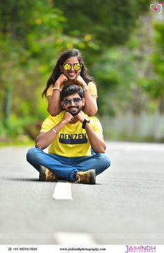 a man and woman sitting on the side of a road with trees in the background