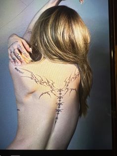 the back of a woman's body with tattoos on it