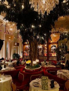 the dining room is decorated with chandeliers and red velvet booths, white tablecloths, and round tables