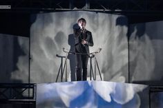 a man standing on top of a stage holding a microphone in front of his face