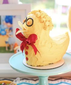 a cake shaped like a chicken sitting on top of a blue plate with a red bow