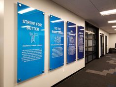 an office hallway with three blue signs on the wall