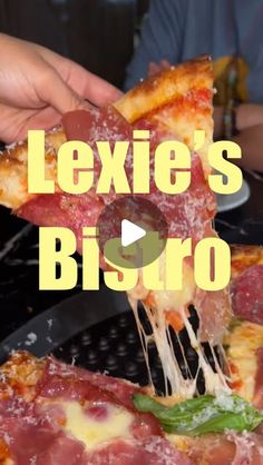 a person taking a slice of pizza from a pan with the words lexiie's bistro on it