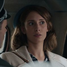 a woman sitting in the back seat of a car talking to a man who is looking at her