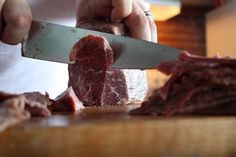 a person cutting meat with a large knife