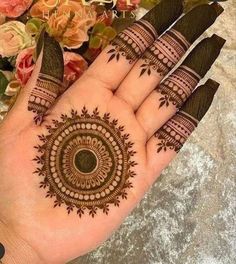 a woman's hand with henna tattoos on it and flowers in the background