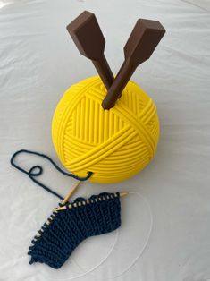 a ball of yarn and two knitting needles on top of a white tablecloth with brown handles