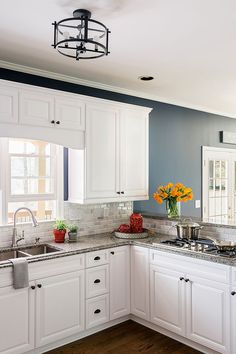 a kitchen with white cabinets and blue walls