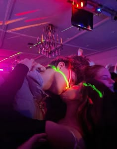 a man and woman kissing in the middle of a room with neon lights around them