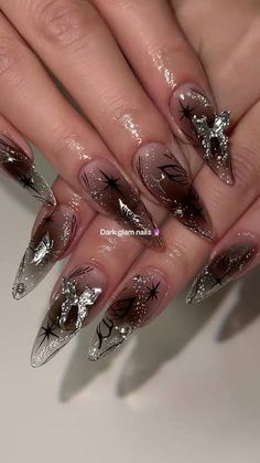 a woman's hand with long, shiny nails and silver decorations on her nails