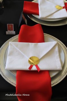 a white plate topped with an envelope and red napkin