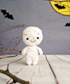 a small white stuffed animal sitting on top of a wooden table next to bats and branches