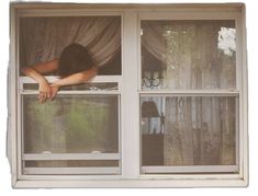 a woman is looking out the window with her head in the curtain and hands on the windowsill