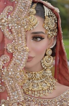 a woman in a bridal outfit with jewelry on her head and veil over her face