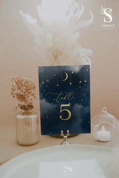 a table topped with a card and vase filled with flowers