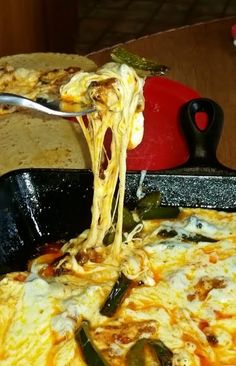 a person is taking a slice of pizza from a pan with cheese and vegetables on it