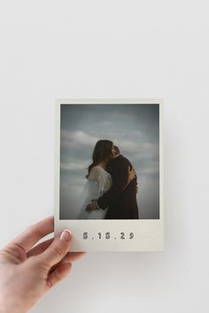 a person holding up a polaroid with the image of two people kissing