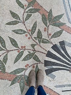 a person standing on top of a tiled floor next to a flowered design with leaves