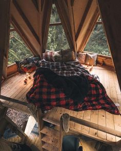 a bed sitting in the middle of a wooden floor next to a tall building with lots of windows