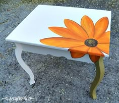 an orange flower painted on top of a white table