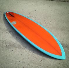 an orange and blue surfboard laying on the ground