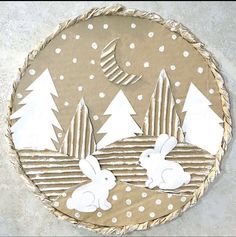 a paper plate that has some rabbits in the snow on it and trees around it