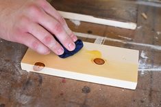 a person is using a blue cloth to cut holes in the wood with a knife