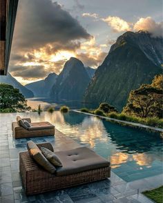 an outdoor pool with chaise lounges and mountains in the background at sunset or sunrise