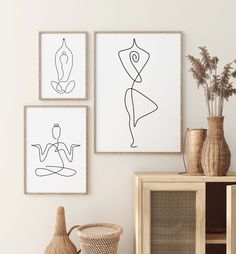 three framed art pieces hang on the wall next to a wicker basket and vase