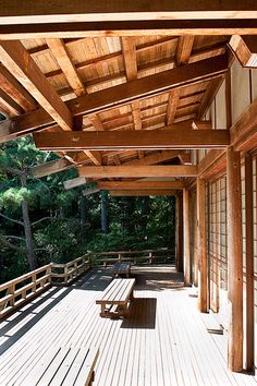 an empty wooden deck with benches and trees in the background