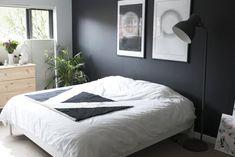 a white bed sitting in a bedroom next to two pictures hanging on the wall above it