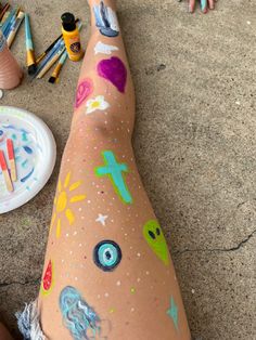 someone has their legs covered in paint and crayons on the ground next to them