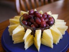 grapes and pineapple slices in a bowl on a blue plate with a wooden table