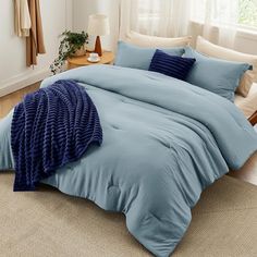 a bed with blue sheets and pillows in a room