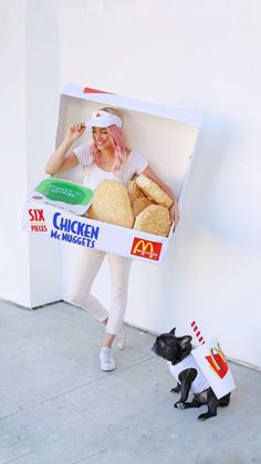 a woman in a cardboard box with a dog dressed up as a hamburger and chicken