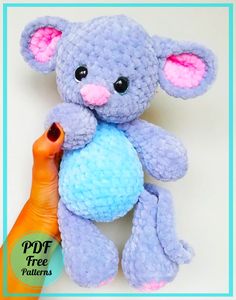 a blue teddy bear with pink ears holding a ball