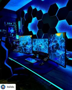 three computer monitors sitting on top of a desk in front of a blue wall with hexagon tiles