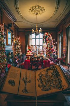 an open book sitting on top of a table in front of christmas trees and other decorations