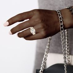 a close up of a person's hand with a chain bracelet and ring on it