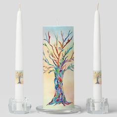 three candles with colorful designs on them sitting next to each other in front of a white background