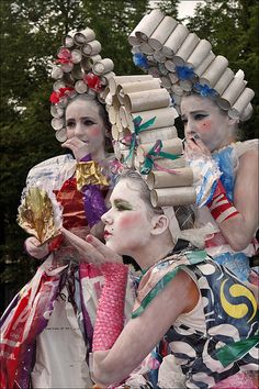 three women dressed in colorful costumes and holding candy wrap around their necks, with trees in the background