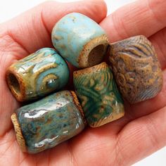 a hand holding five beads in different colors